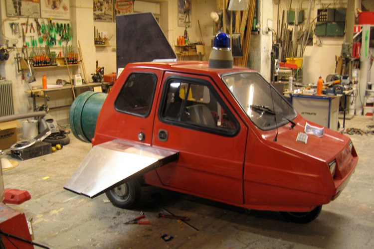 En röd bil på tre hjul